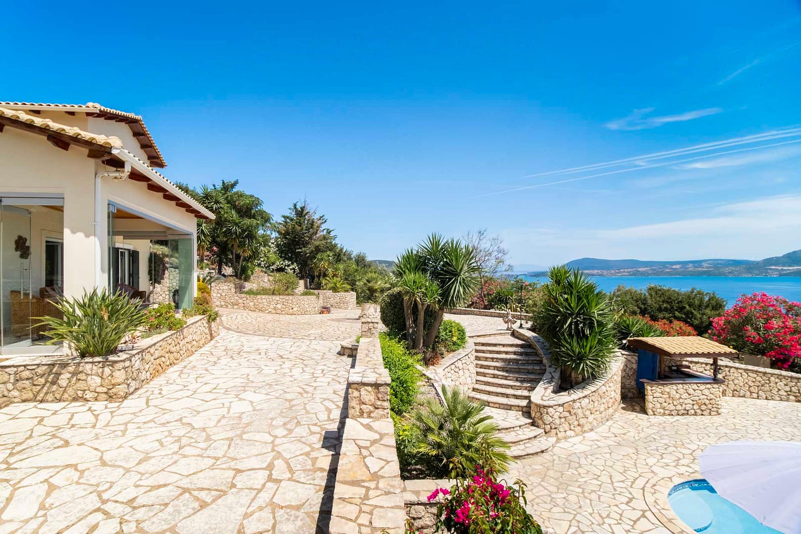 view towards the glas veranda the stairs to the pool and the sea views